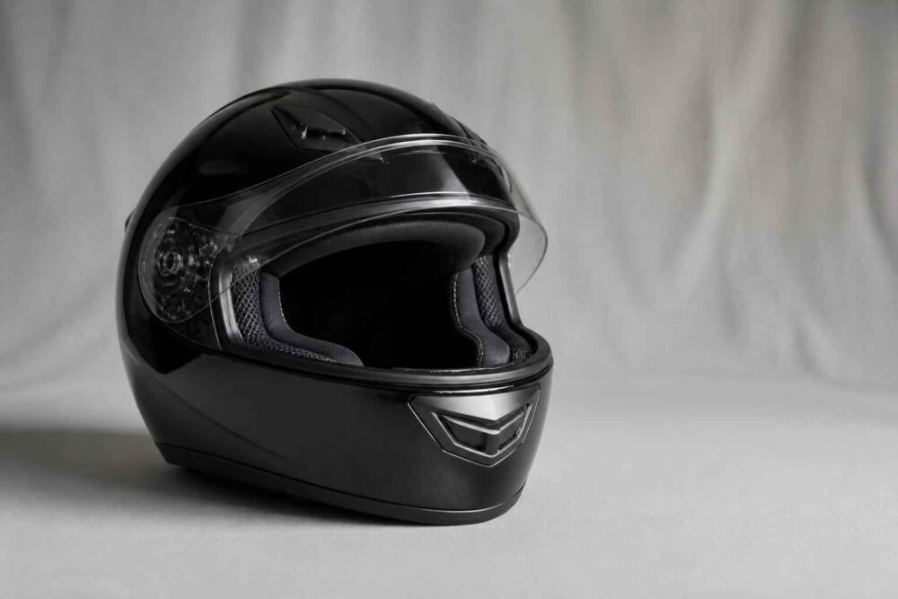 Czarny pełnotwarzowy kask motocyklowy na jasnym tle