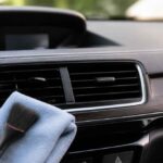 Pędzel i ściereczka przy kratce nawiewu w samochodzie, obok butelki ze środkiem czyszczącym