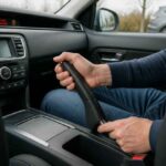 Mężczyzna zaciąga ręczny hamulec na konsoli środkowej samochodu