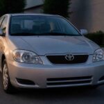 Srebrna Toyota Corolla zaparkowana przed nowoczesnym budynkiem o zmierzchu