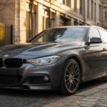 Szare BMW sedan zaparkowane na brukowanej ulicy wśród miejskiej zabudowy